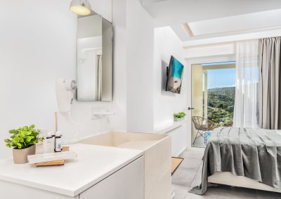 Minimal suite sleeping area with natural light and modern furnishings, Myzith Luxury Suites, Keri, Zakynthos, Greece.
