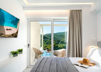 Minimal suite sleeping area with natural light and modern furnishings, Myzith Luxury Suites, Keri, Zakynthos, Greece.